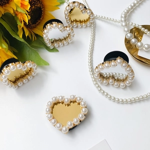Detail of five heart-shaped phone grips with gold mirror finish and pearl borders