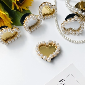 Detailed view of heart-shaped phone grip with gold mirror finish and pearl embellishments