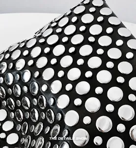 Gros plan d'un sac en cuir noir avec des rivets métalliques argentés de tailles variées