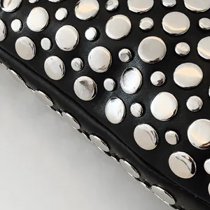 Détail du sac en cuir noir avec des rivets argentés brillants de style industriel punk