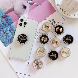 Detail of luxury metal bow phone grip with 3D love lettering on a green smartphone