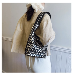 Détails des rivets argentés sur le sac bandoulière en cuir noir au style punk moderne