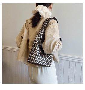 Détail d'un sac hobo punk marron foncé avec de grands rivets en métal argenté et une coupe souple