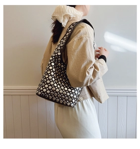 Détail du sac à bandoulière avec des rivets argentés sur un matériau en cuir de qualité