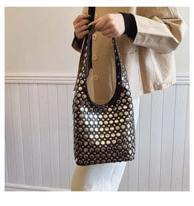 Détail d'un sac hobo noir avec rivets métalliques argentés au style punk moderne