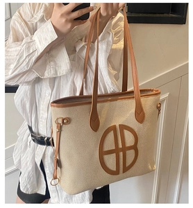 Detail of canvas tote bag showing beige woven fabric and brown leather handle stitching