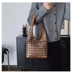 Détail de rivets argentés sur sac hobo en cuir marron au style punk moderne