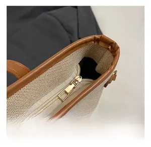 Close-up of golden metal zipper and brown leather trim on canvas tote bag detail