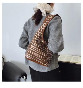 Sac hobo marron avec détails de rivets argentés porté sur un pull en maille gris chiné