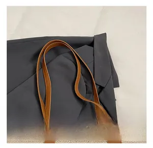Detail of canvas tote bag with brown leather handles and metallic rivet accents