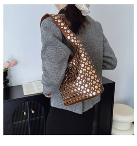 Détail d'un sac à bandoulière marron avec rivets argentés et design style moto rétro
