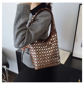 Détail du sac bandoulière en cuir marron avec rivets argentés porté par le mannequin