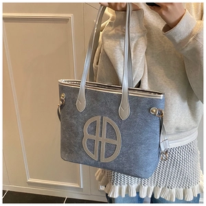Detail of blue denim tote bag with circular logo, silver strap and metal hook