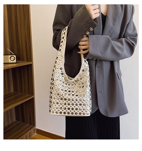 Sac hobo blanc avec clous métalliques argentés porté avec un blazer gris