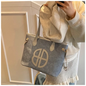 Detail of light blue textured tote bag with circular logo and golden hardware buckle