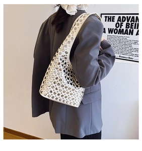 Gros plan d'un sac sous le bras en cuir blanc avec rivets argentés sur un mannequin