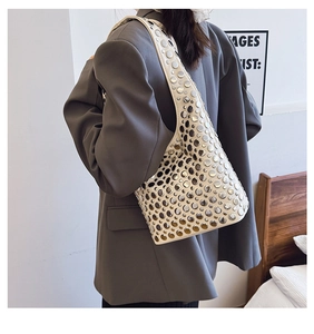 Détail d'un sac à bandoulière blanc avec rivets argentés porté par un mannequin de dos