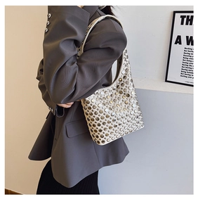 Détail d'un sac hobo chic de couleur crème avec rivets métalliques et esthétique punk y2k