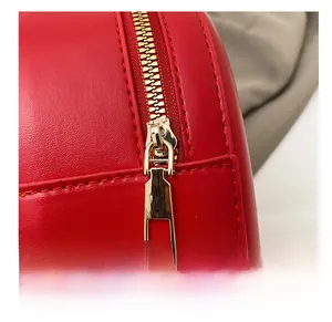 Gros plan d'une fermeture éclair dorée lisse sur un sac à main en cuir rouge vif