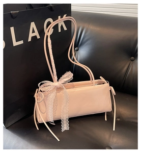 Detail of pink faux leather baguette bag featuring delicate white lace bows and side ties