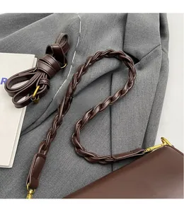 Detail of dark brown leather handbag with adjustable smooth and woven shoulder straps