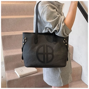 Detail of minimalist black matte tote bag featuring circular cutout and gold hardware