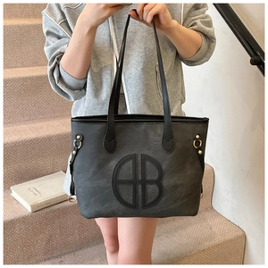 Detail view of large black tote bag with embossed B logo and gold hardware accents