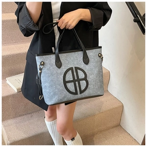 Detail of grey felt tote bag with leather handles and circular logo decoration