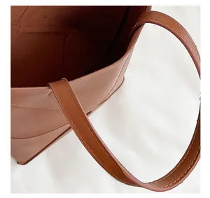 Détail de l'ouverture pratique et de la bandoulière en cuir de ce sac seau marron chic