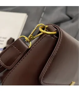 Detailed close-up of golden metal hooks and fine stitching on dark brown leather bag