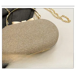 Detail of champagne gold evening clutch showing shimmering glitter fabric and metal bow clasp