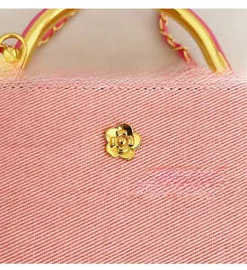 Macro shot of pink denim fabric texture with golden floral logo and metal zipper detail