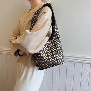 Sac à épaule marron avec clous argentés style motard vintage porté par un mannequin
