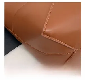 Vue macro des coutures précises et du cuir marron de qualité sur un sac seau