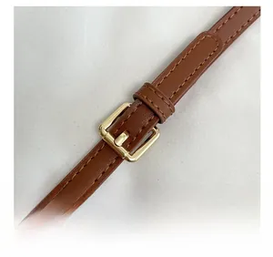 Détail de la bandoulière réglable en cuir marron avec boucle dorée et coutures de précision
