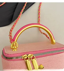 Macro shot of pink denim bag featuring golden semi-circular handle and floral zipper pull