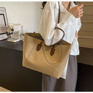 Détail du grand sac cabas kaki avec anses marron porté par une femme élégante