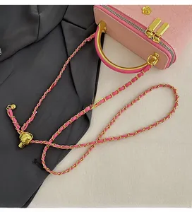 Close-up of pink quilted bag with golden flower clasp and chain strap detail