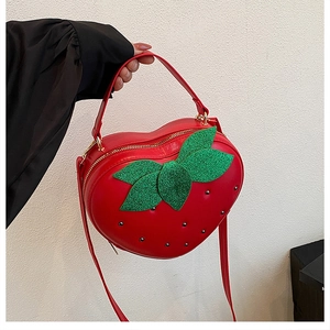 Détail du sac à main cœur en forme de fraise rouge avec feuilles en paillettes et zip doré