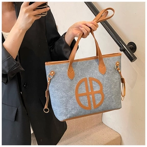 Detail of blue felt tote bag showing AB leather logo and brown leather shoulder strap
