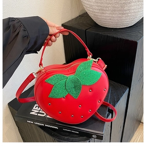 Détail du sac fraise rouge avec feuilles en paillettes vertes et rivets en métal
