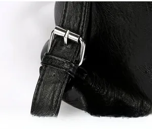 Macro detail of the durable silver metal buckle and litchi texture on the black tote bag