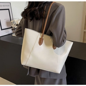 Vue détaillée d'un sac cabas minimaliste en cuir blanc avec anses brunes sur un mannequin