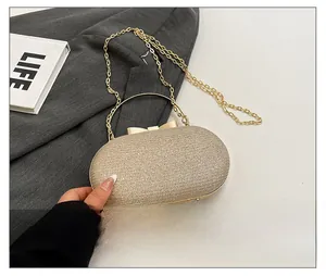 Detail of champagne gold sequin evening bag with crystal bow and metal chain strap