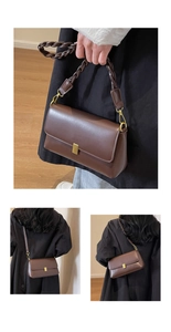 Detail view of brown leather shoulder bag featuring a woven strap and gold buckle closure