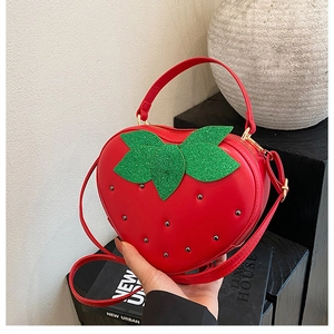 Détail du sac fraise rouge avec feuilles pailletées vertes et clous argentés décoratifs