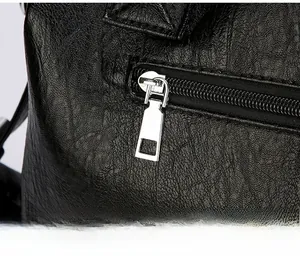 Close-up of smooth silver metal zipper and hardware on black pebbled leather tote bag