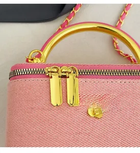 Detail of pink fabric bag showing gold circular handle and floral zipper charm