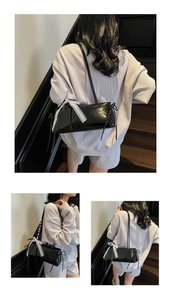 Detail of black patent leather shoulder bag with white lace bow and sleek rectangular shape