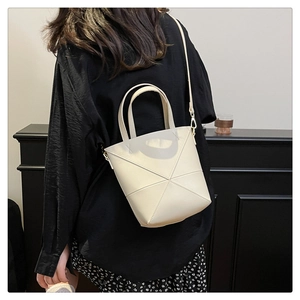 Détail du sac seau crème minimaliste avec coutures géométriques sur le modèle
